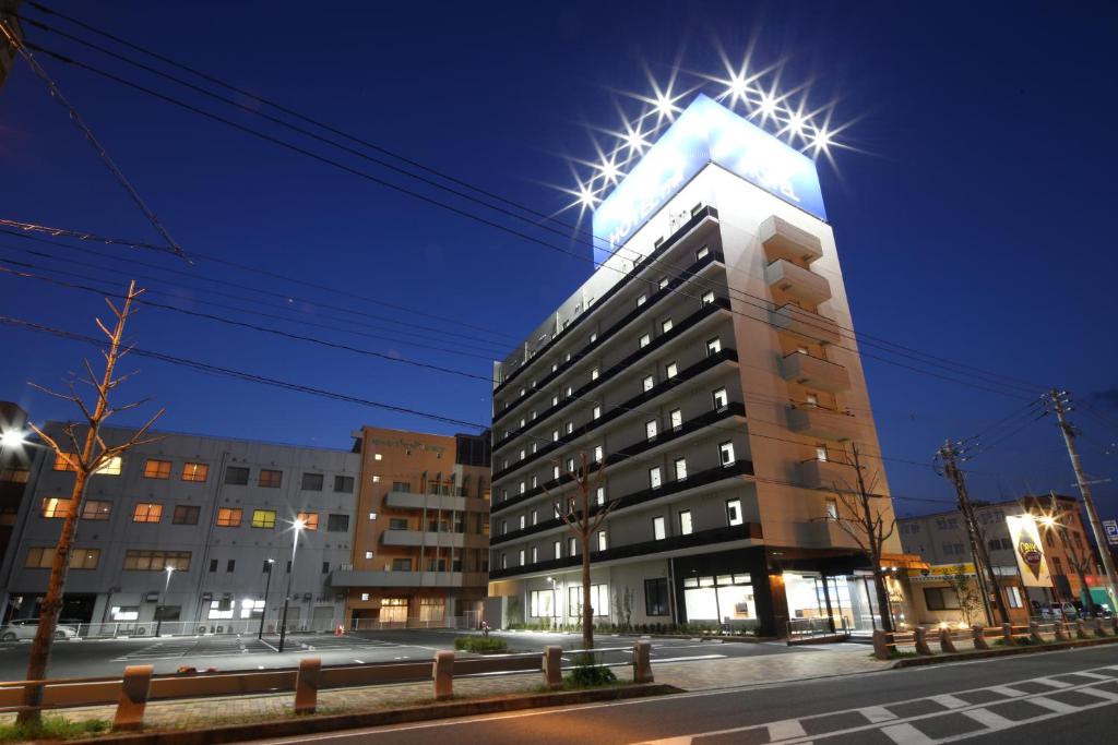 Un grand bâtiment avec des lumières au-dessus dans l'établissement AB Hotel Yukuhashi, à Yukuhashi