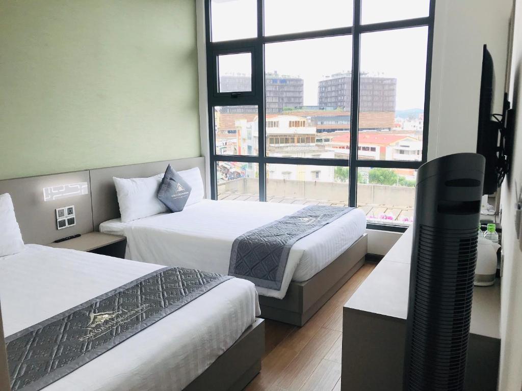 una camera d'albergo con due letti e una grande finestra di Kim Oanh Orchids Hotel a Da Lat