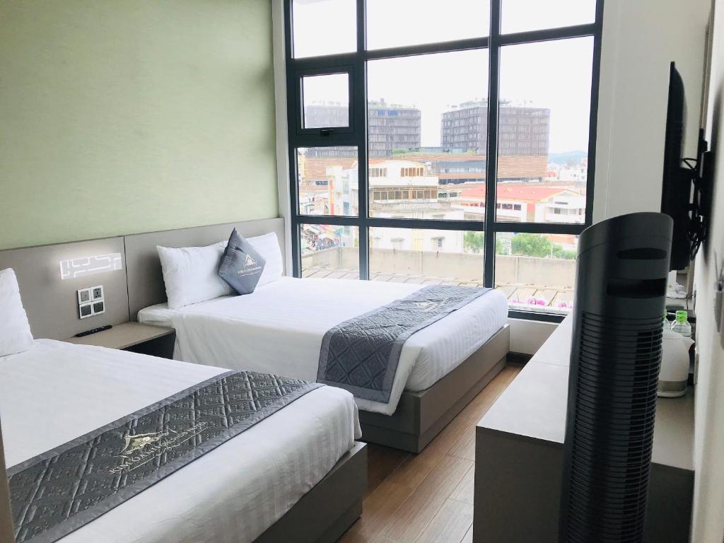 a hotel room with two beds and a large window at Kim Oanh Orchids Hotel in Da Lat