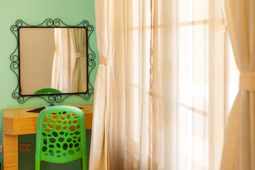 a mirror on a wall above a desk with a green chair at Summer Ya B&amp;B in Huxi