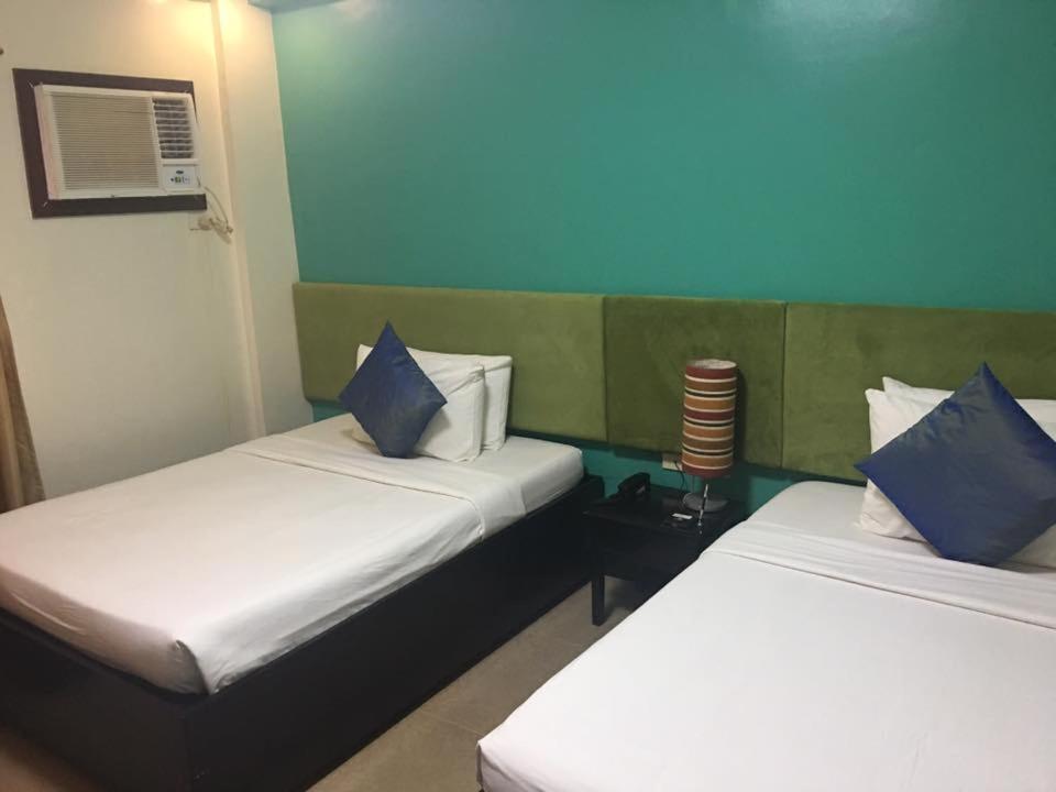 a room with two beds with blue and white pillows at Residencia Boracay in Boracay