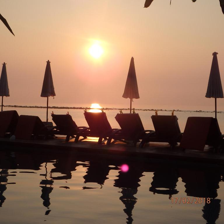 a group of chairs and umbrellas next to a pool at Montien House - SHA Plus in Chaweng