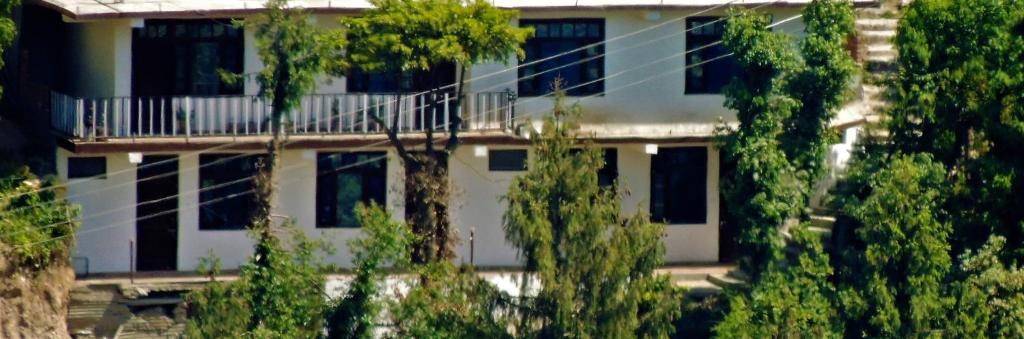 un bâtiment blanc avec des arbres devant lui dans l'établissement Peaceful Dalhousie, à Dalhousie