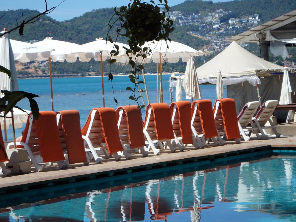 a row of orange lounge chairs next to a swimming pool at Montien House - SHA Plus in Chaweng