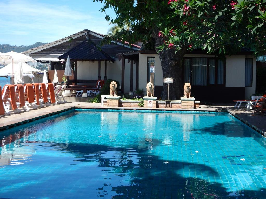 a large blue swimming pool with chairs and a house at Montien House - SHA Plus in Chaweng
