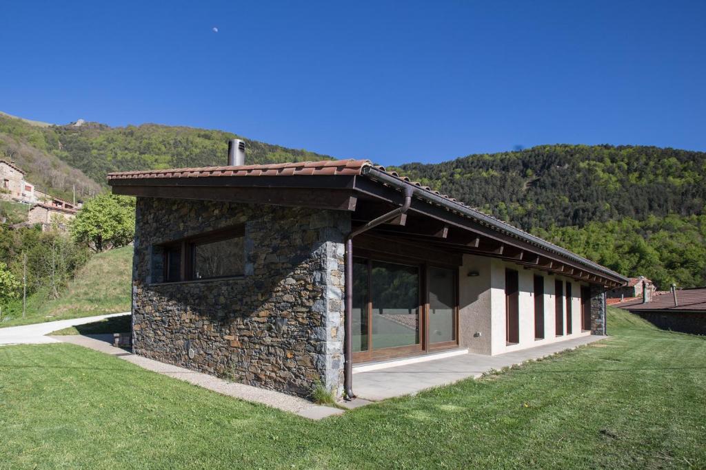 a stone building with a large window on a grass field at Cal Sadurní in Bruguera