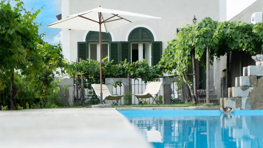 een zwembad met een parasol en stoelen en een huis bij Il Casino di Donna Maria in Mormanno