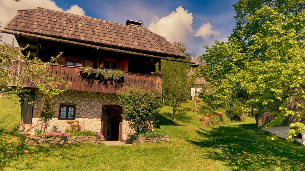 una casa antigua con techo de madera en un campo verde en Domačija Koklej - Apartments Vintage Vacation en Luče