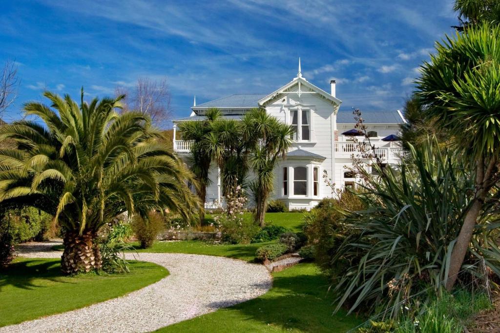 a white house with palm trees and a gravel driveway at Sennen House Boutique Accommodation in Picton