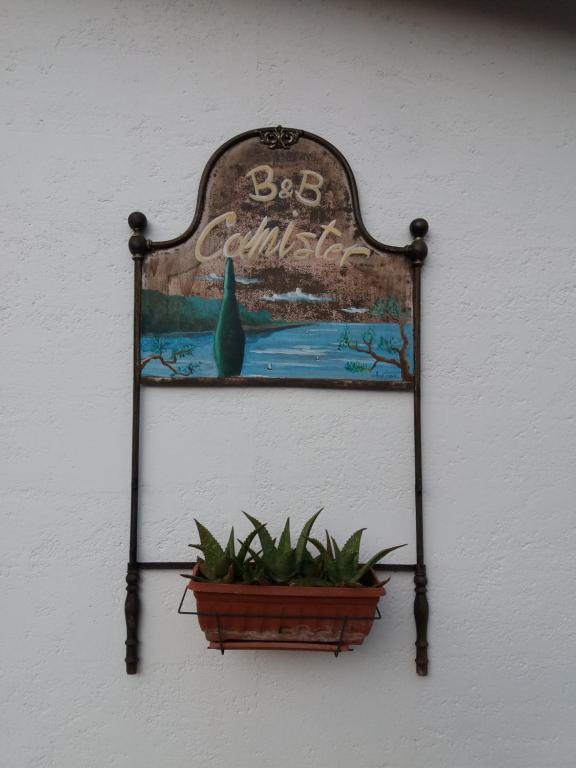 a sign hanging on a wall with a potted plant at B&B Camister in Toscolano Maderno