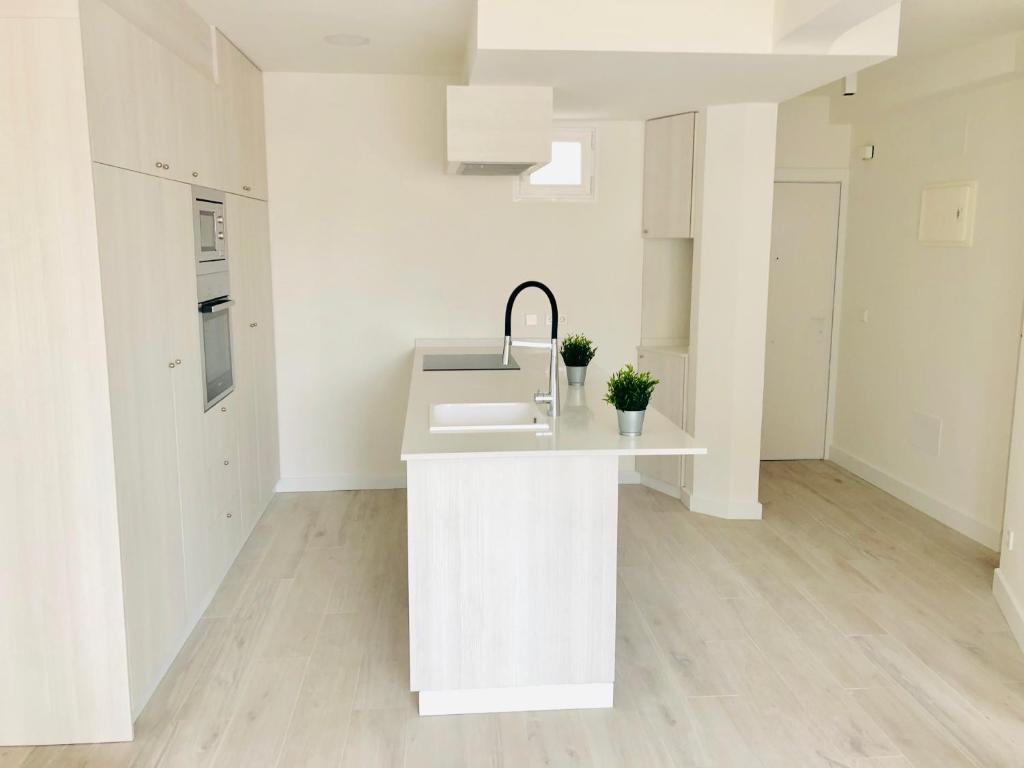a white kitchen with a sink and a counter at Pisos con Piscina Barrio Exclusivo-WizinkCenter in Madrid