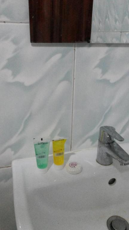 a bathroom sink with two cups on top of it at Hotel Dot Com Entebbe in Entebbe