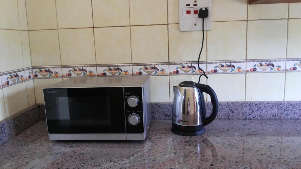 a microwave sitting on a counter next to a coffee pot at Hotel Dot Com Entebbe in Entebbe