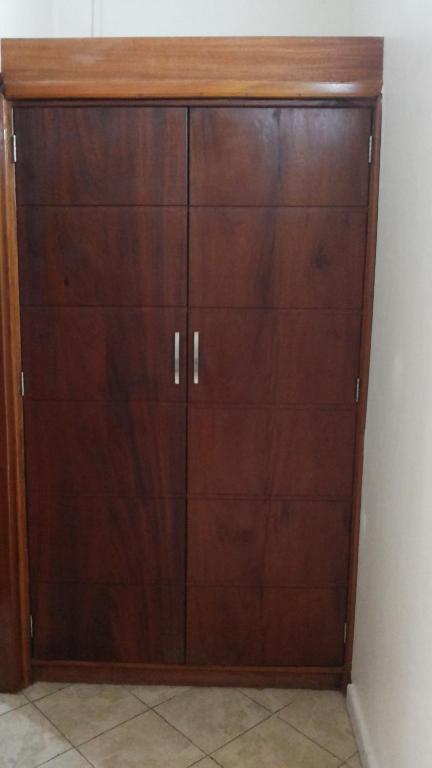 a wooden cabinet with four drawers in a room at Hotel Dot Com Entebbe in Entebbe