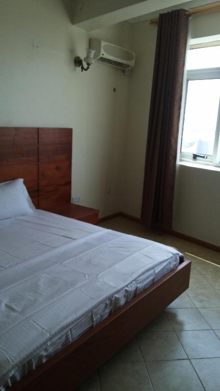 a bedroom with a large bed with a window at Hotel Dot Com Entebbe in Entebbe