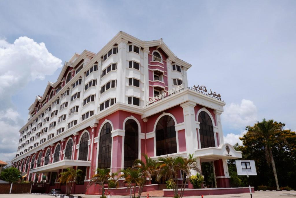 ein rosa und weißes Gebäude mit Palmen davor in der Unterkunft Parkview Hotel in Kampong Jerudong