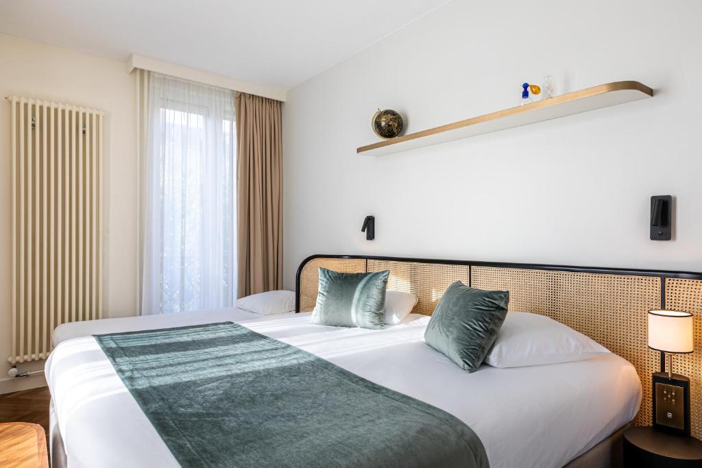 a bedroom with a large white bed with green pillows at Hotel Le Friedland in Paris