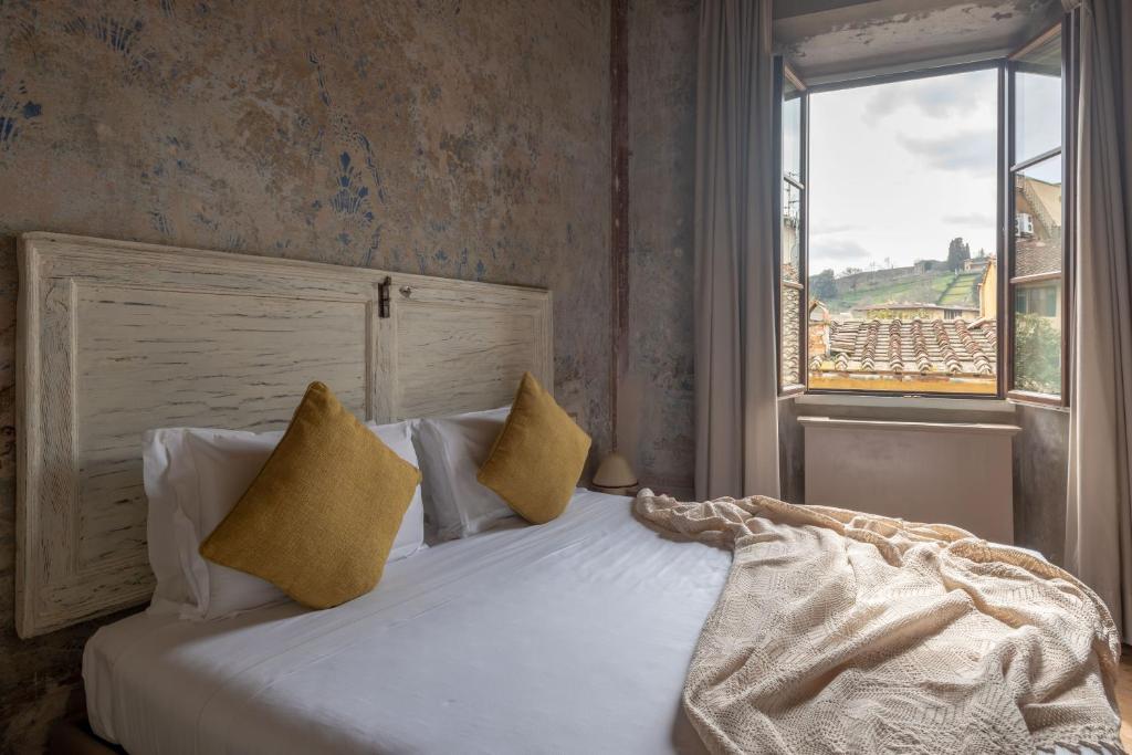 a bedroom with a white bed with yellow pillows and a window at Residenza La Musa Amarcord in Florence