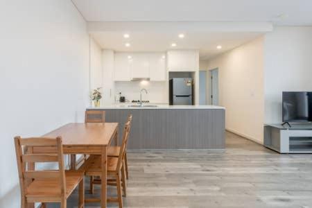 cocina y comedor con mesa de madera y sillas en Nice and Clean Apartment with Free Wifi and Netflix, en Bankstown