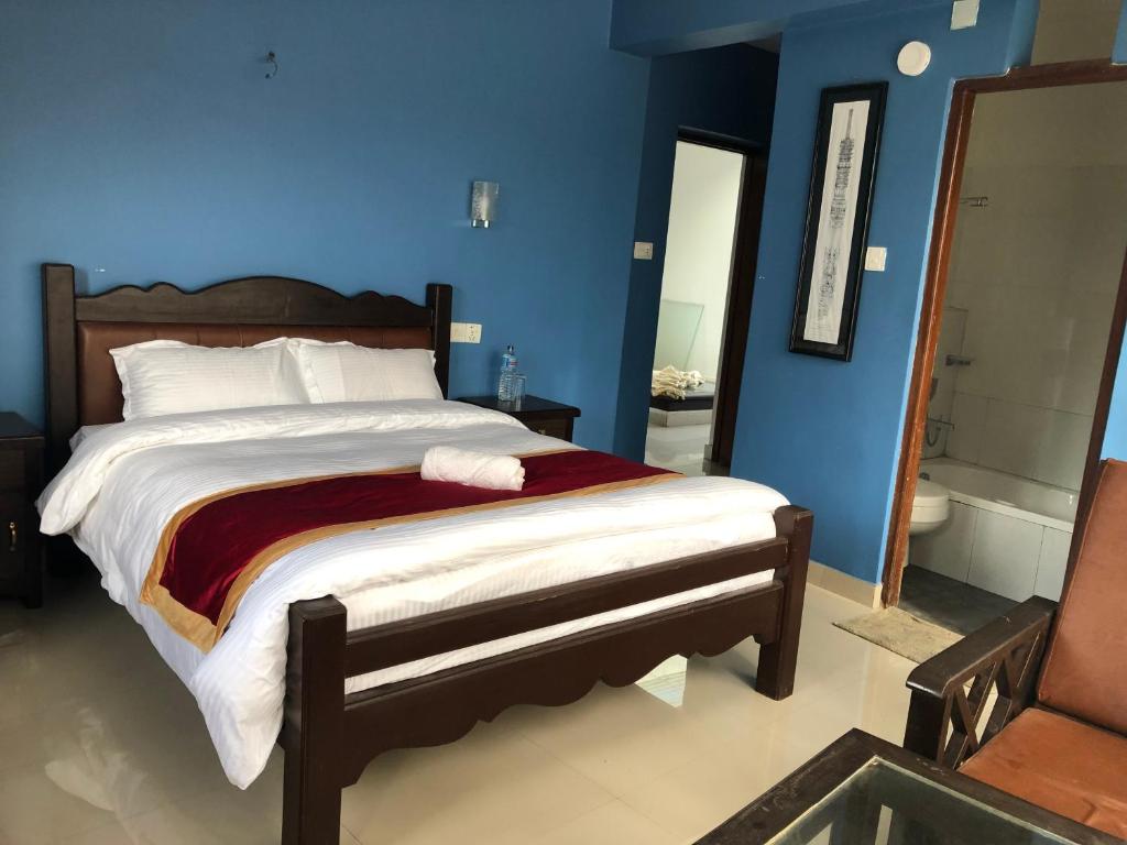 a bedroom with a large bed and a blue wall at The Hotel in Bandīpur