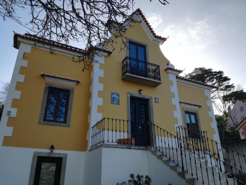a yellow and white house with a balcony at Guest House Villa dos Poetas in Sintra