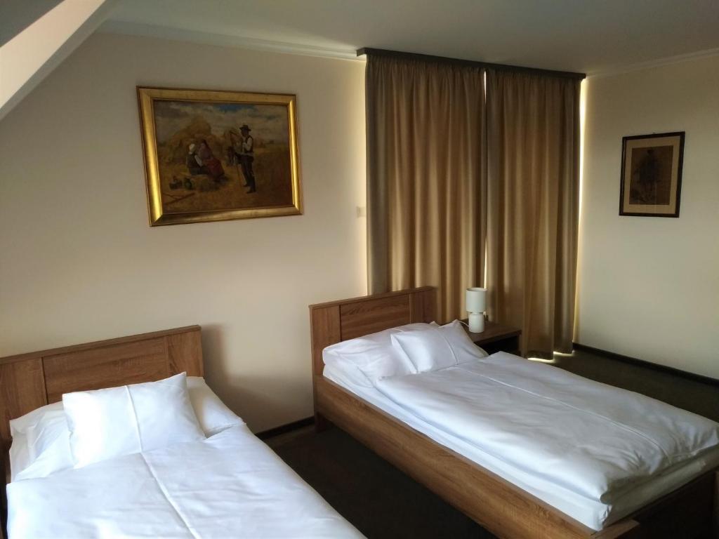 2 bedden in een hotelkamer met witte lakens bij St. Hubert Vendégház in Hortobágy
