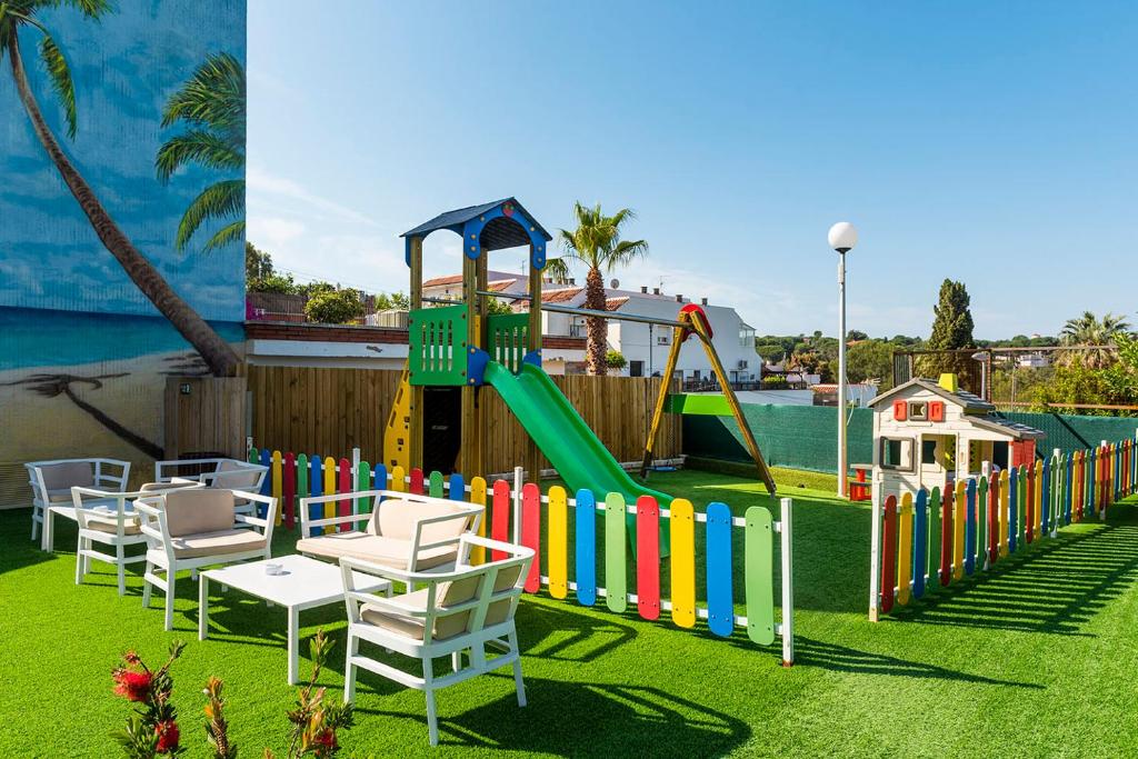 a playground with a slide and chairs on the grass at Apartaments Els Llorers in Lloret de Mar