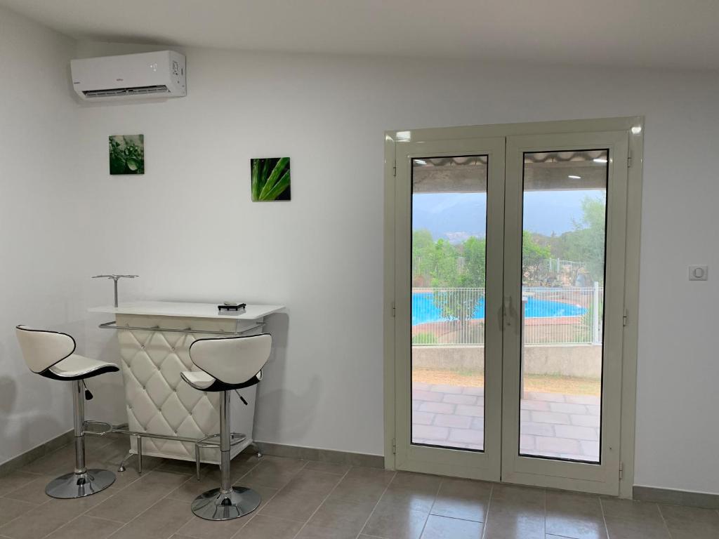 une chambre avec deux tabourets et une porte avec une piscine dans l'établissement Appartement corse olmeto, à Olmeto
