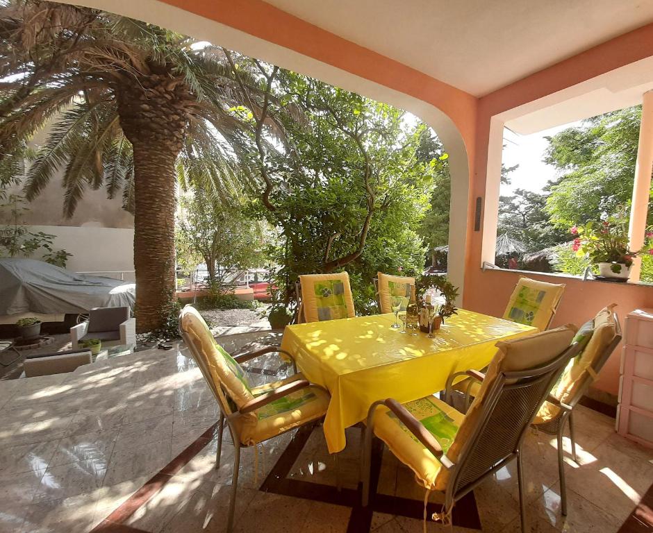 a dining room with a yellow table and chairs at Guest House Prskalo in Makarska