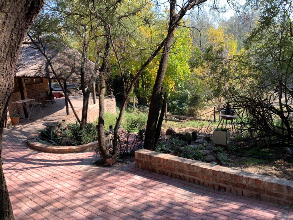 a brick walkway in a park with trees and bushes at Riverstay in Kroonstad