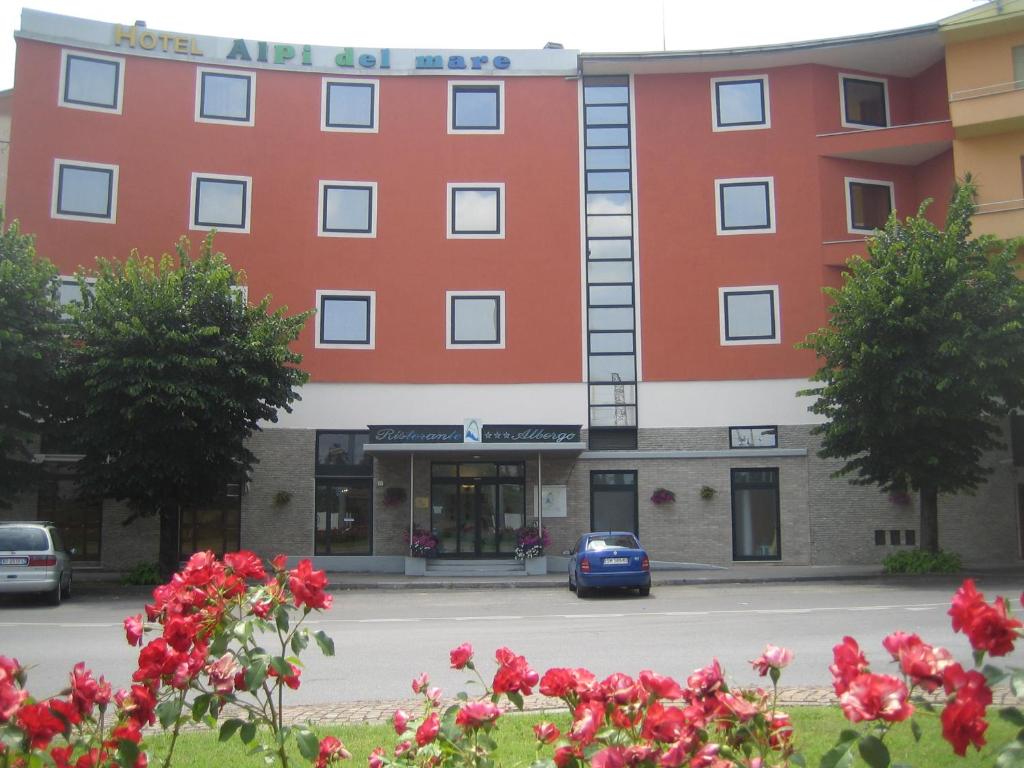 a red building with a car parked in front of it at Hotel Alpi Del Mare in Mondovì