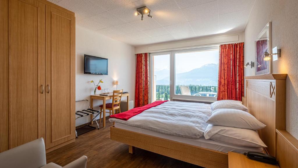 Schlafzimmer mit einem Bett und einem großen Fenster in der Unterkunft Hôtel Splendide in Crans-Montana