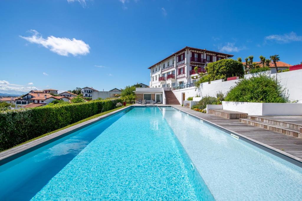 uma piscina com água azul em frente a um edifício em Hotel Itsas Mendia em Bidart