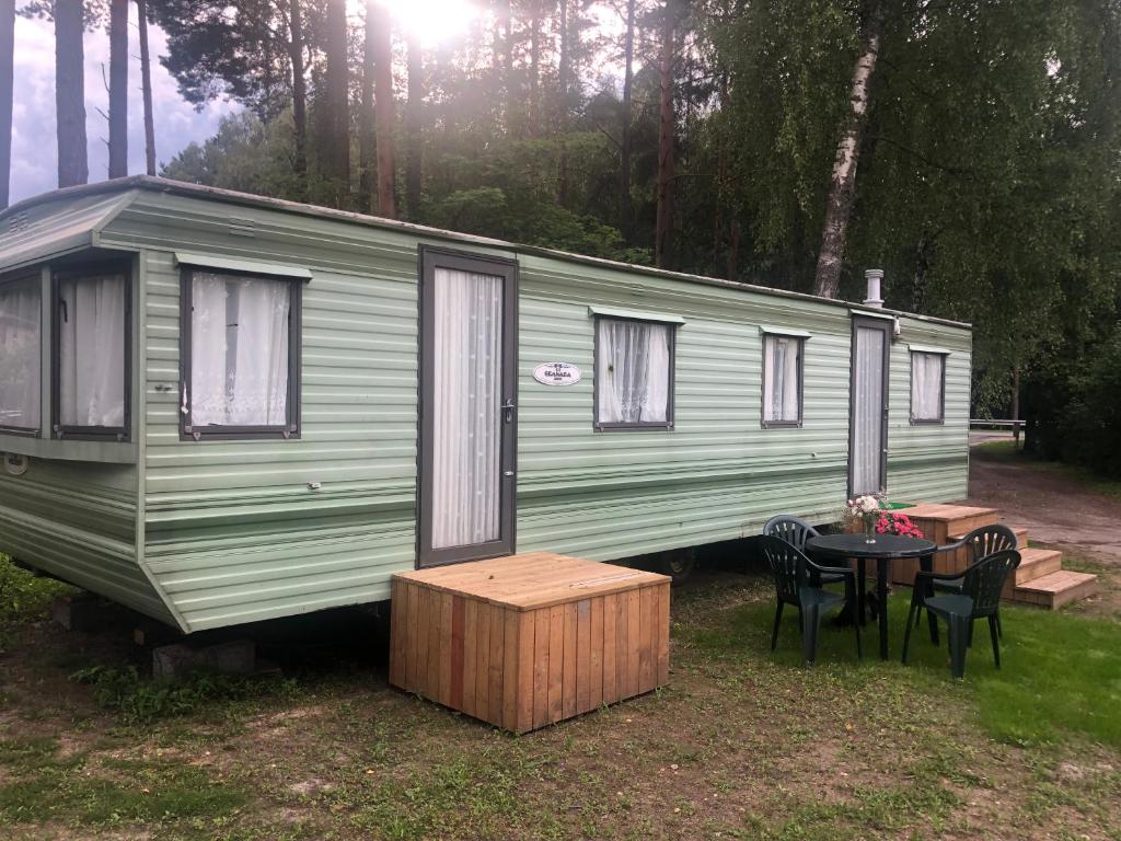 una caravana verde con una mesa y sillas frente a ella en Summer beach house en Saulkrasti