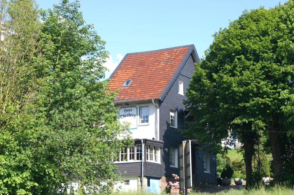 ein großes Haus mit rotem Dach in der Unterkunft Pension Oberberg in Lindlar