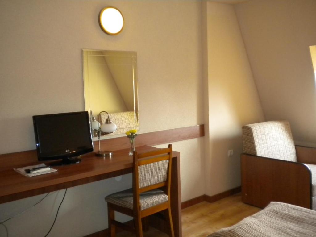 Habitación con escritorio, TV y espejo. en Hotel Crisana Arad en Arad