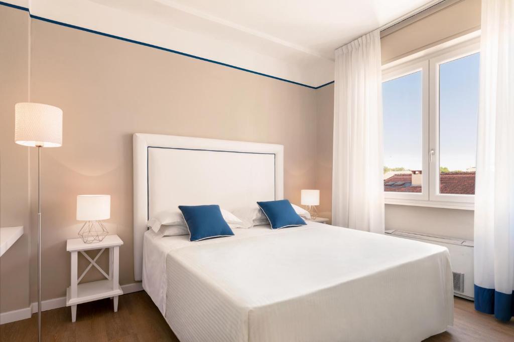 a bedroom with a large white bed with blue pillows at Hotel Sina Astor in Viareggio