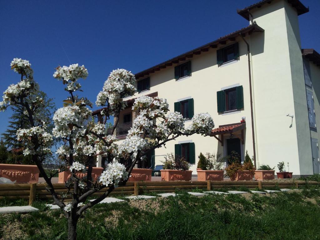 un edificio con un árbol delante de él en Cascina Rosa Camilla, en Carpeneto