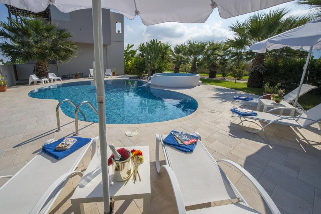 a swimming pool with two chairs and an umbrella at Luxury Xenos Villa 2 With 4 Bedrooms , Private Swimming Pool, Near The Sea in Tigaki