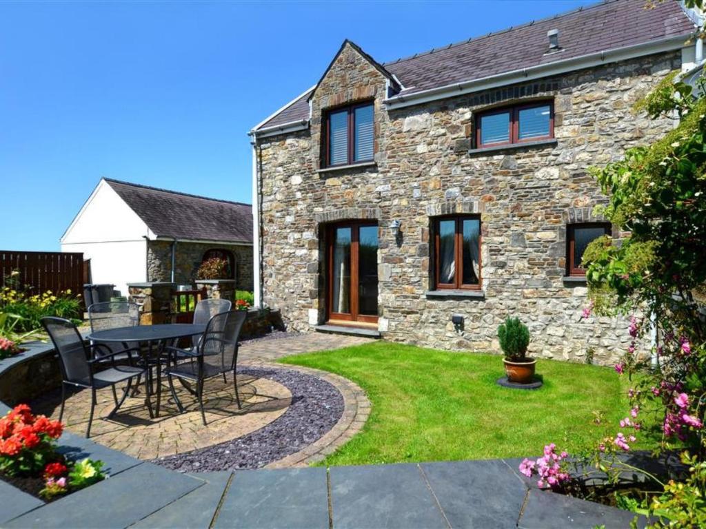 a stone house with a table and chairs in the yard at Holiday Home Palmerston Barn by Interhome in Haverfordwest