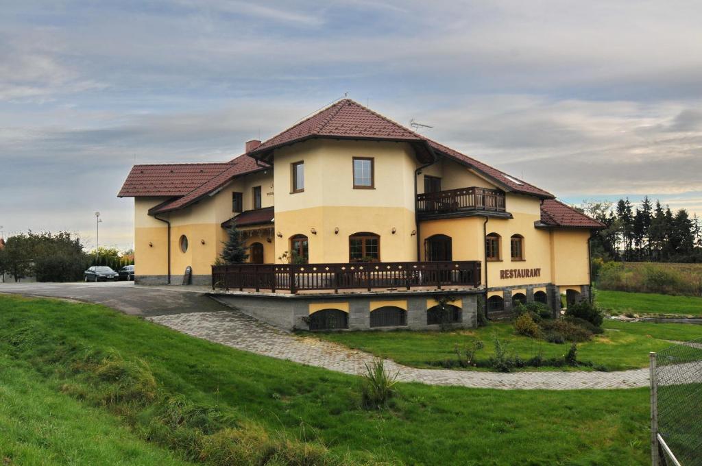 a large yellow house with a balcony on a hill at Penzion Starý dvůr in Nové Dvory