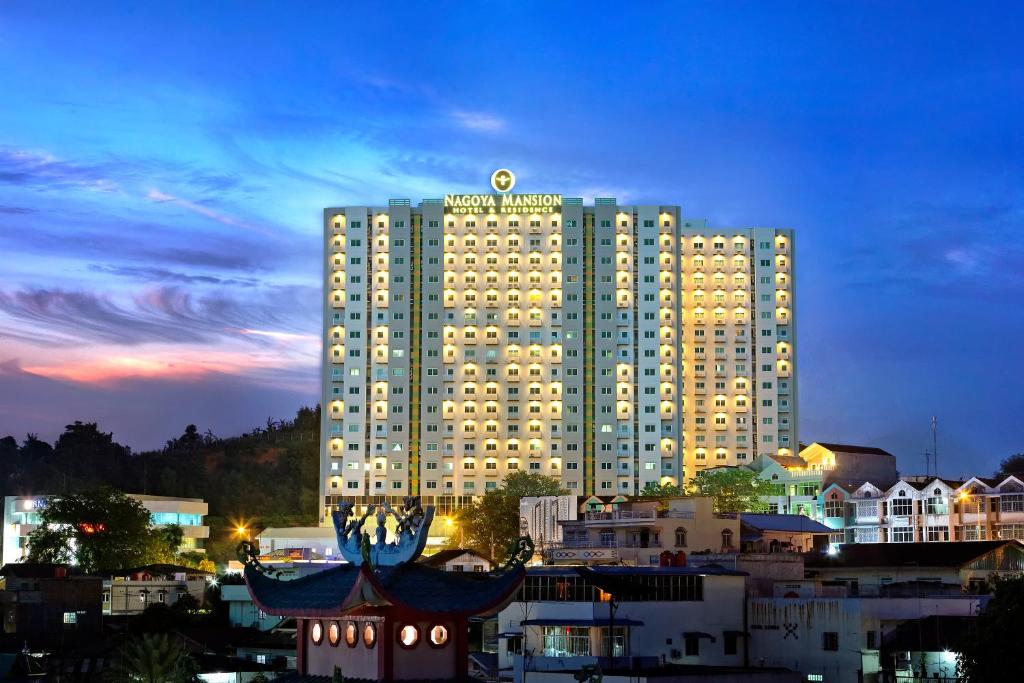 a large hotel building with a lit up building at Nagoya Mansion Hotel and Residence in Nagoya