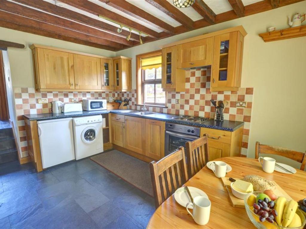 カーナーヴォンにあるHoliday Home Llanfaglan House by Interhomeのキッチン(木製テーブル、フルーツプレート付)