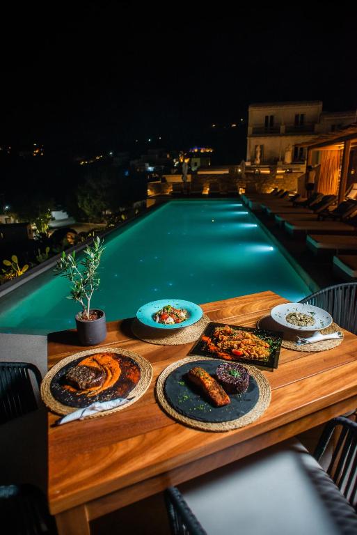 a wooden table with plates of food on top of a pool at Super Paradise Hotel in Super Paradise Beach