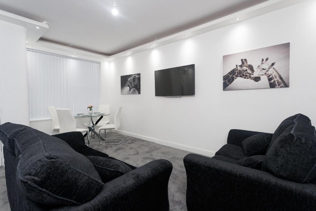 a living room with two chairs and a tv on a wall at Leeds House in Leeds