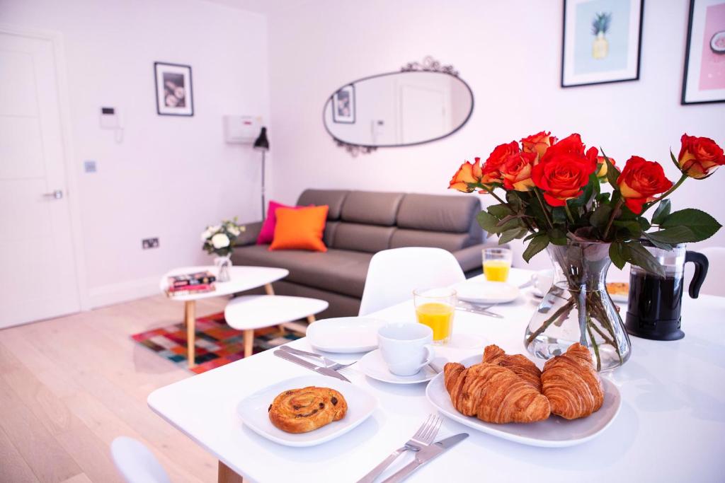 een woonkamer met een tafel met rozen en croissants bij New West End Apartments by Indigo Flats in Londen