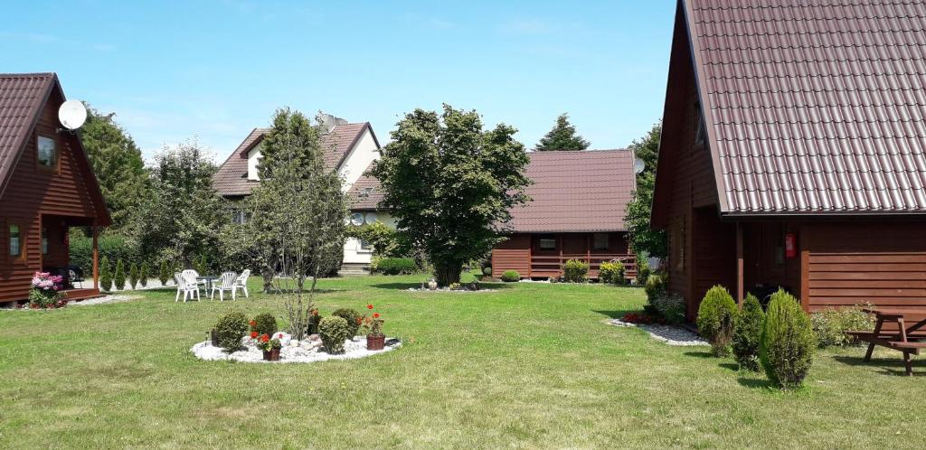a yard with houses and a garden with flowers in it at Agroturystyka i Domki Zacisze in Jarosławiec