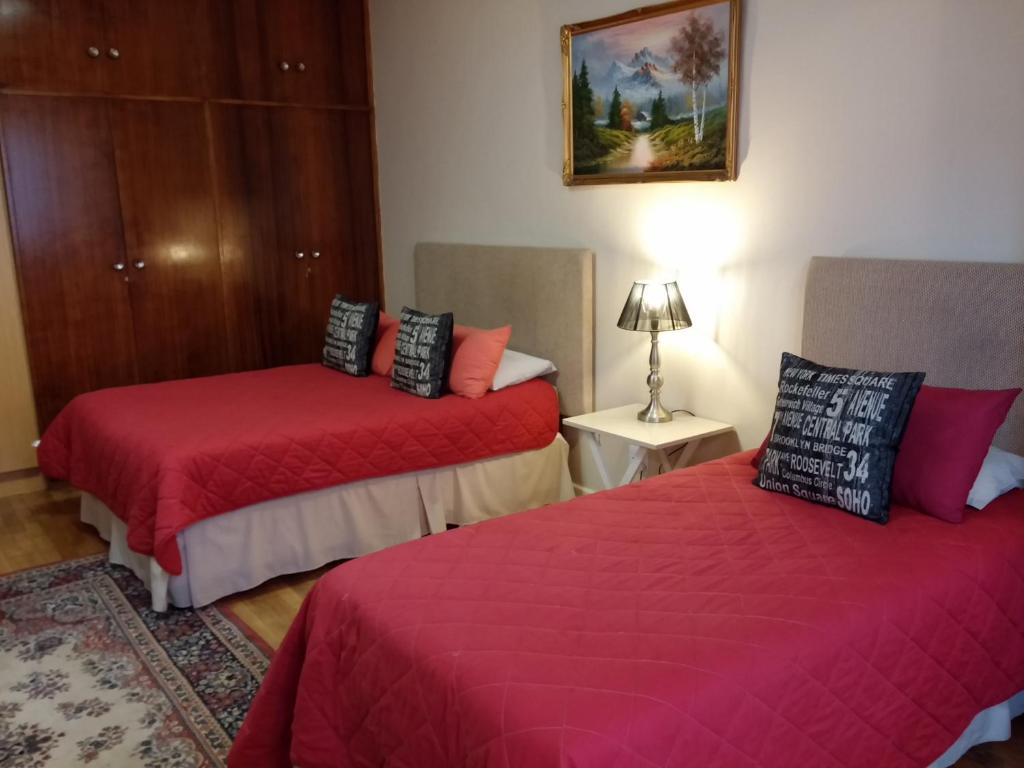 1 dormitorio con 2 camas con sábanas rojas y lámpara en Uitenhage Apartments en Uitenhage