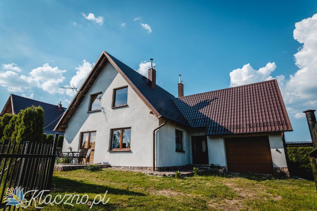ein weißes Haus mit braunem Dach in der Unterkunft Dom Kłączno z kominkiem w okolicy lasów i jeziora in Studzienice
