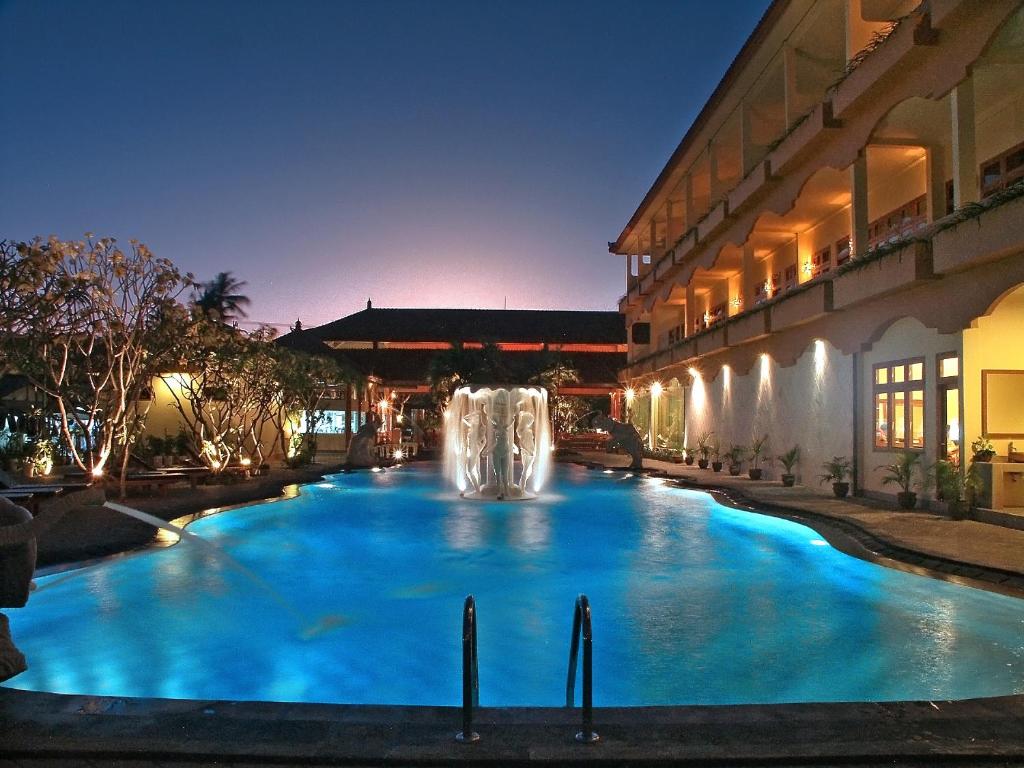 a swimming pool with a fountain in front of a building at Febri's Hotel & Spa in Kuta